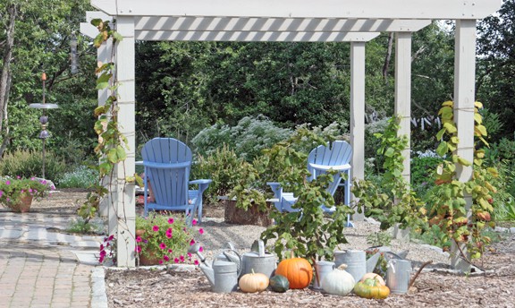 The display of watering cans and pumpkins/squash serves two purposes. It is a way of savoring autumn, and a way to fill an area that is not yet planted, so there isn't as much bare mulch.