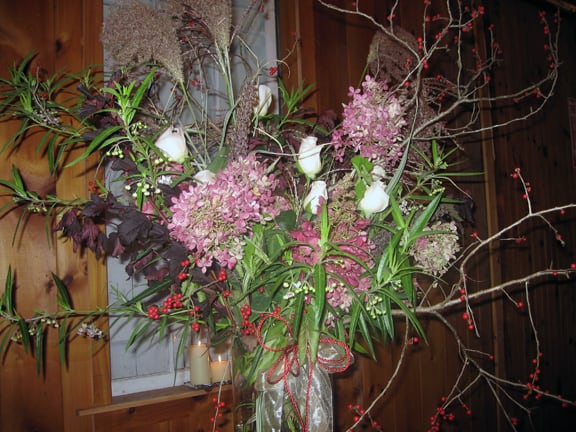 Hydrangeas, winterberry holly, and assorted other flowers filled the tall vases.
